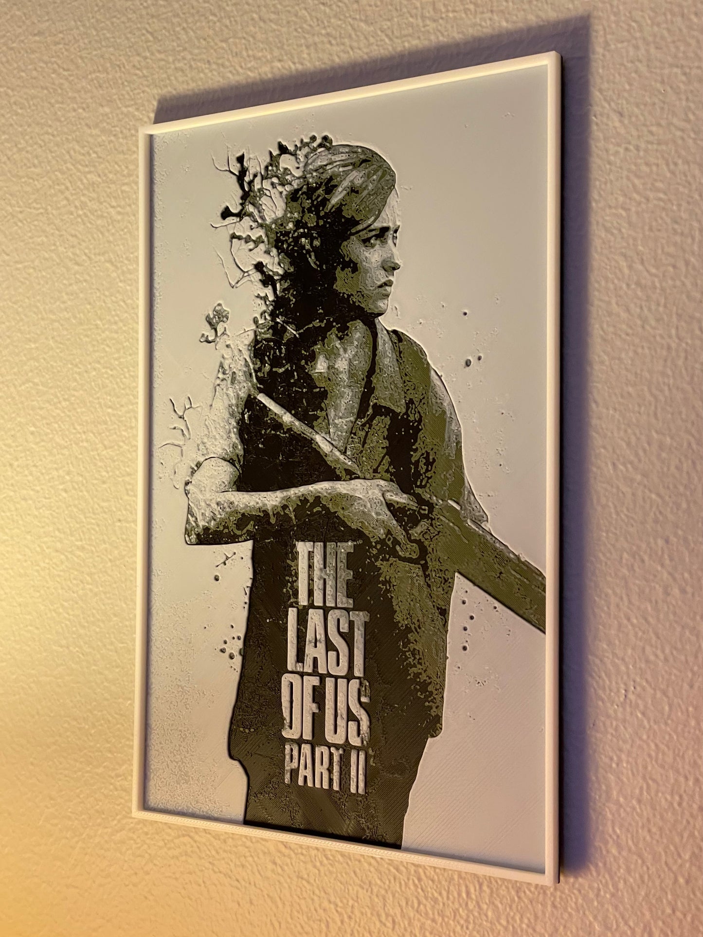 Framed poster of a character from 'The Last of Us Part II' on a wall.