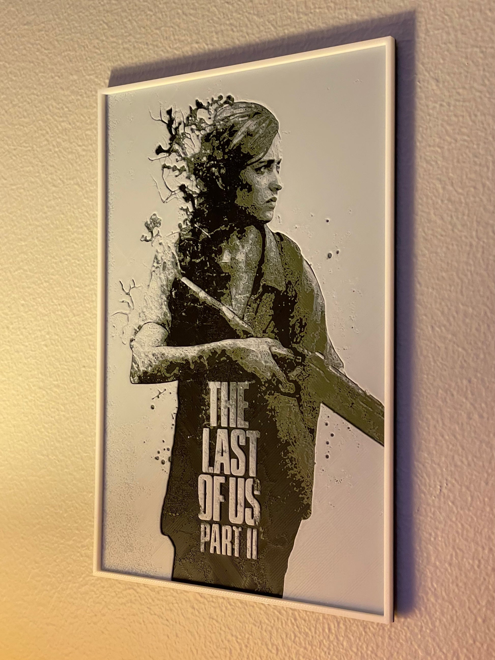 Framed poster of a character from 'The Last of Us Part II' on a wall.