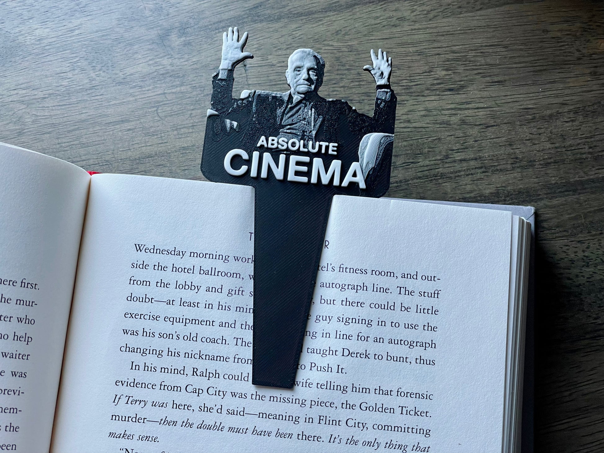 Bookmark shaped like a person with 'Absolute Cinema' text on an open book