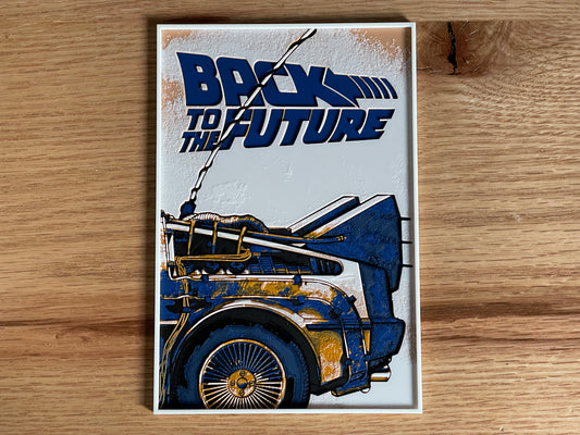 Poster of 'Back to the Future' with a blue and gold car design on a wooden surface.
