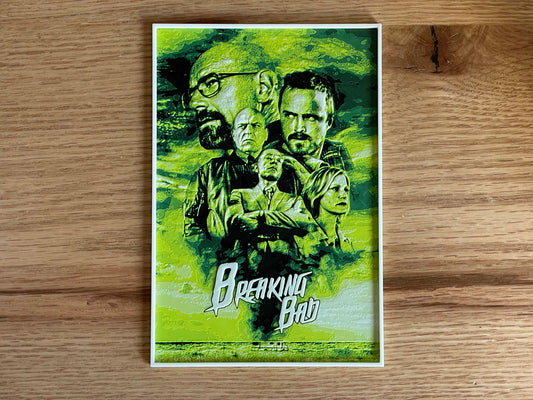 Poster of 'Breaking Bad' with characters on a green background, placed on a wooden surface.