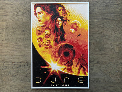 Movie poster for 'Dune Part One' with characters and space-themed design on a wooden surface.