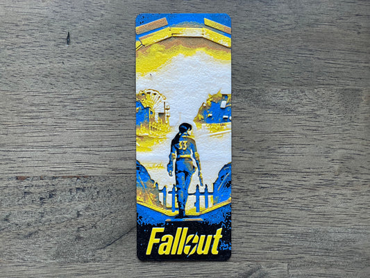bookmark with 'Fallout' design featuring a character and architecture on a wooden surface