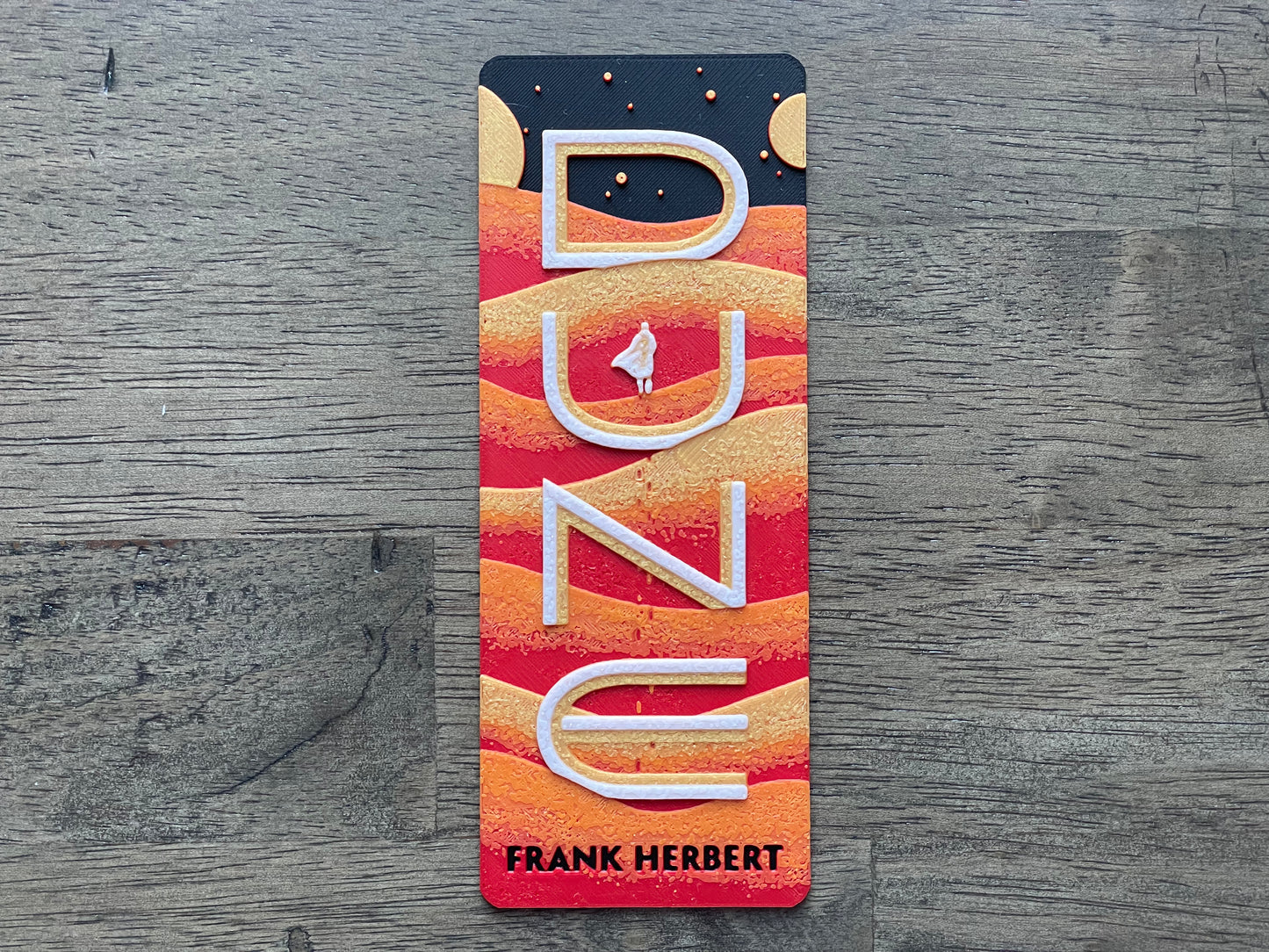 Bookmark with 'Dune' by Frank Herbert design on a wooden surface