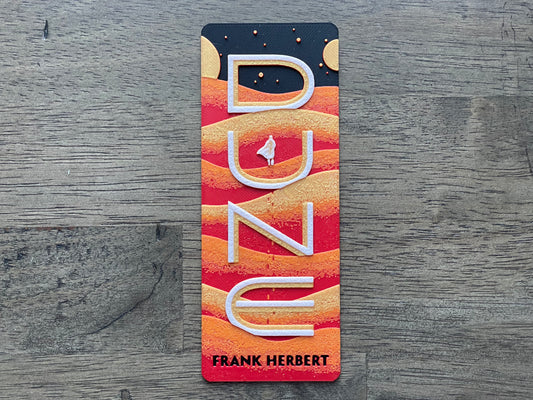Bookmark with 'Dune' by Frank Herbert design on a wooden surface