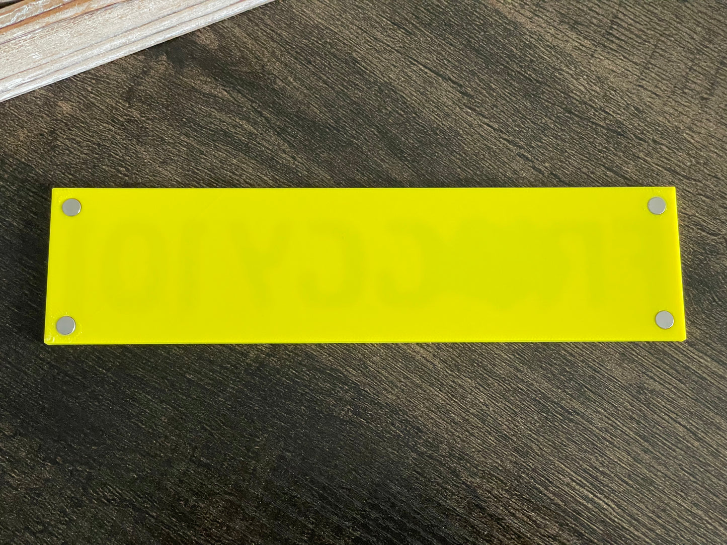 Yellow rectangular plate with metallic screws on a wooden surface
