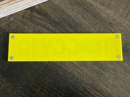 Yellow rectangular plate with metallic screws on a wooden surface