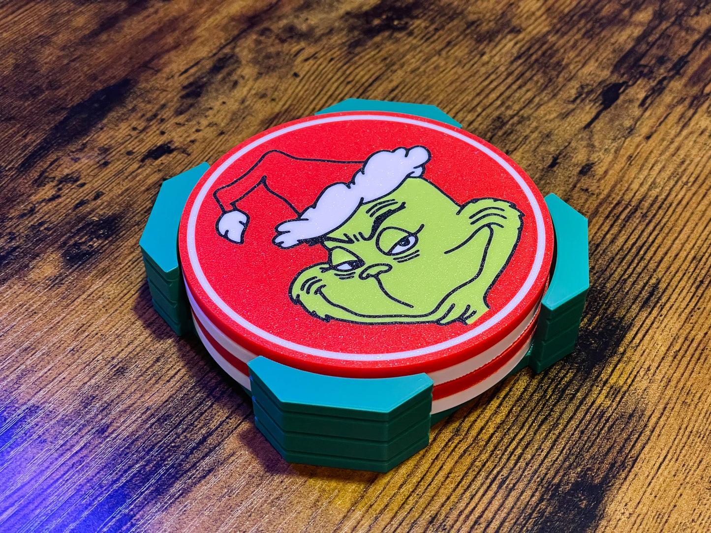 Stack of coasters with a Grinch design on a wooden surface