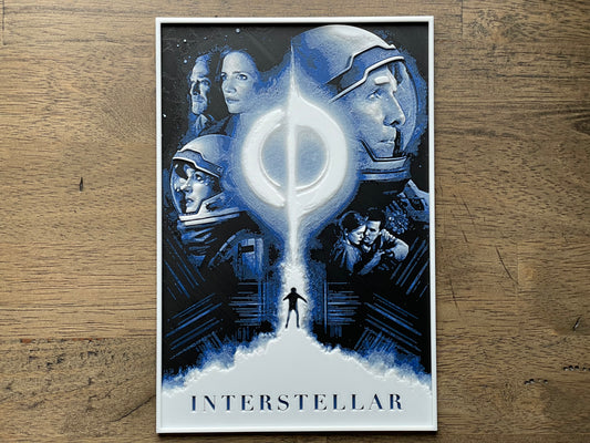 Poster of 'Interstellar' with characters and a wormhole or black hole graphic on a wooden surface