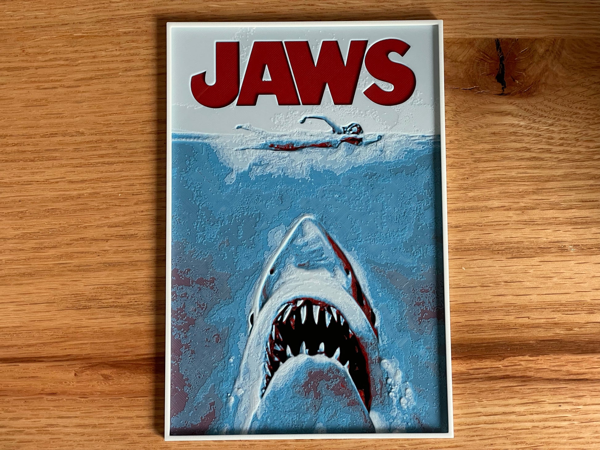 Movie poster for 'Jaws' with a shark and swimmer on a wooden surface