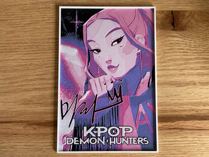 Poster of a character from 'K-Pop Demon Hunters' with stylized text on a wooden surface