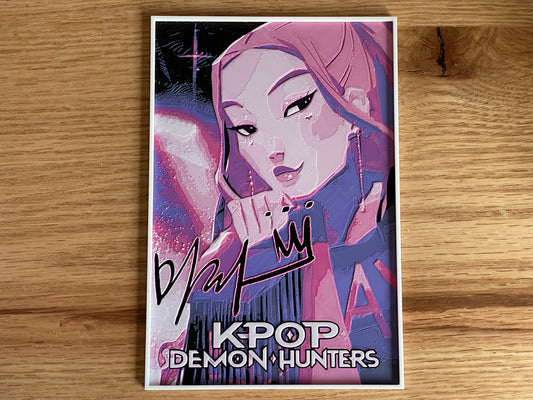 Poster of a character from 'K-Pop Demon Hunters' with stylized text on a wooden surface