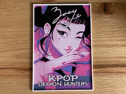 Poster of a stylized character with 'K-POP DEMON HUNTERS' text on a wooden surface