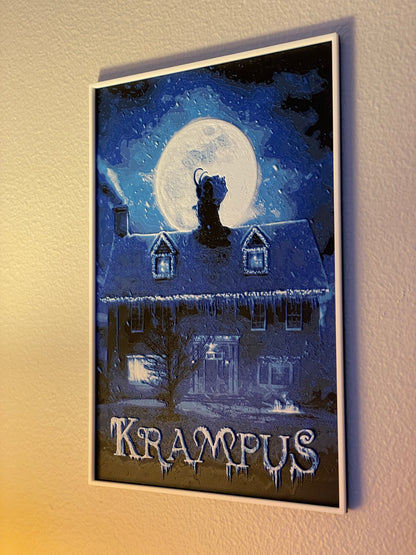 Framed Krampus poster with a house and moonlit sky on a wall.