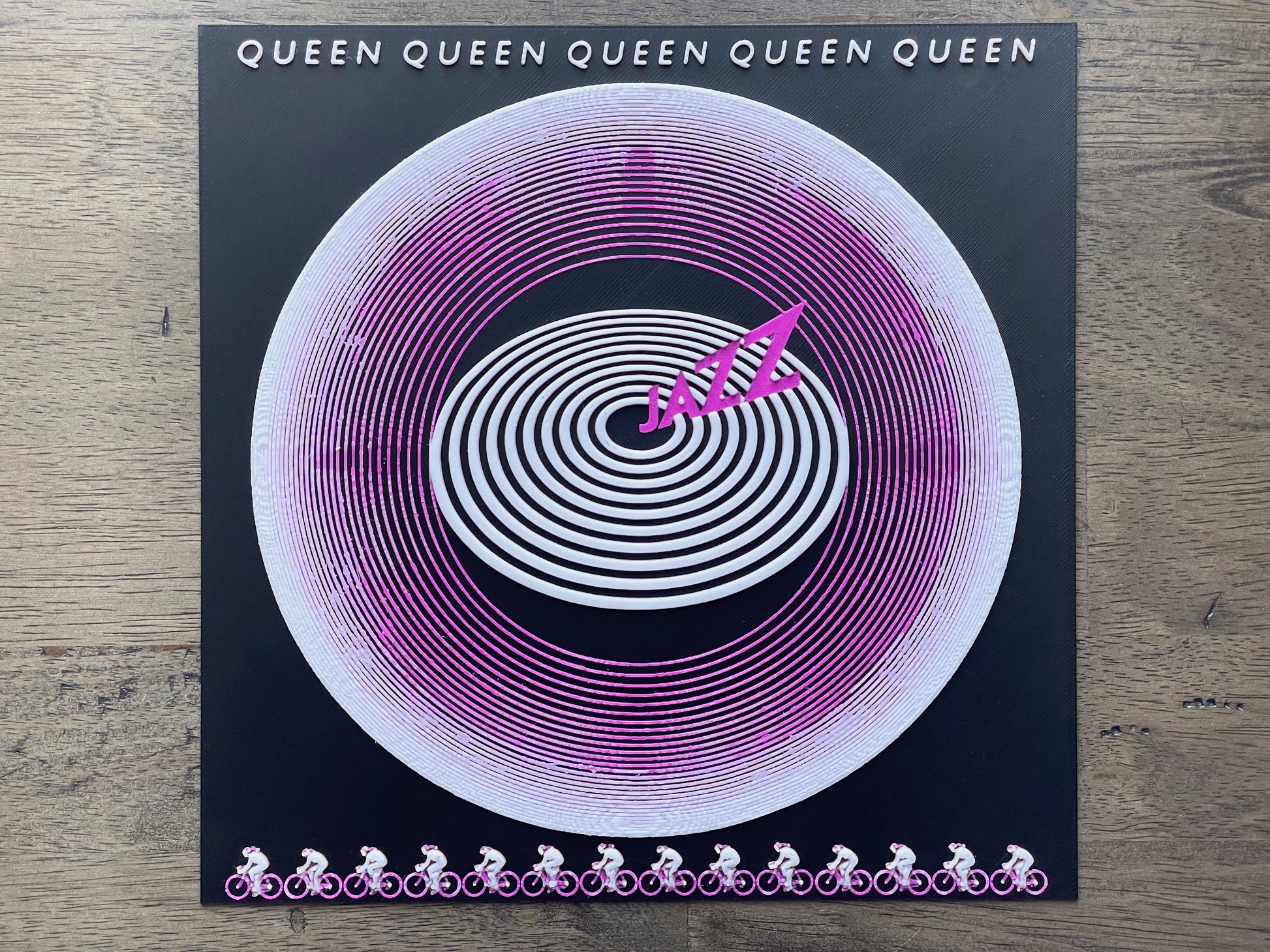 Vinyl record with spiral design and 'Queen' branding on a wooden surface