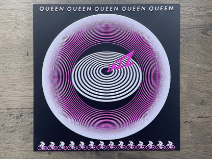Vinyl record with spiral design and 'Queen' branding on a wooden surface
