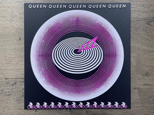 Vinyl record with spiral design and 'Queen' branding on a wooden surface
