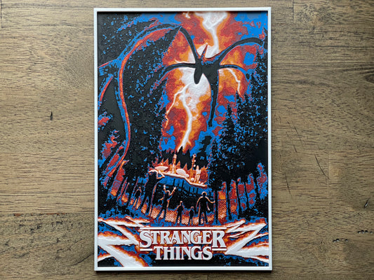 Poster of 'Stranger Things' with a dark sky and silhouette design on a wooden surface
