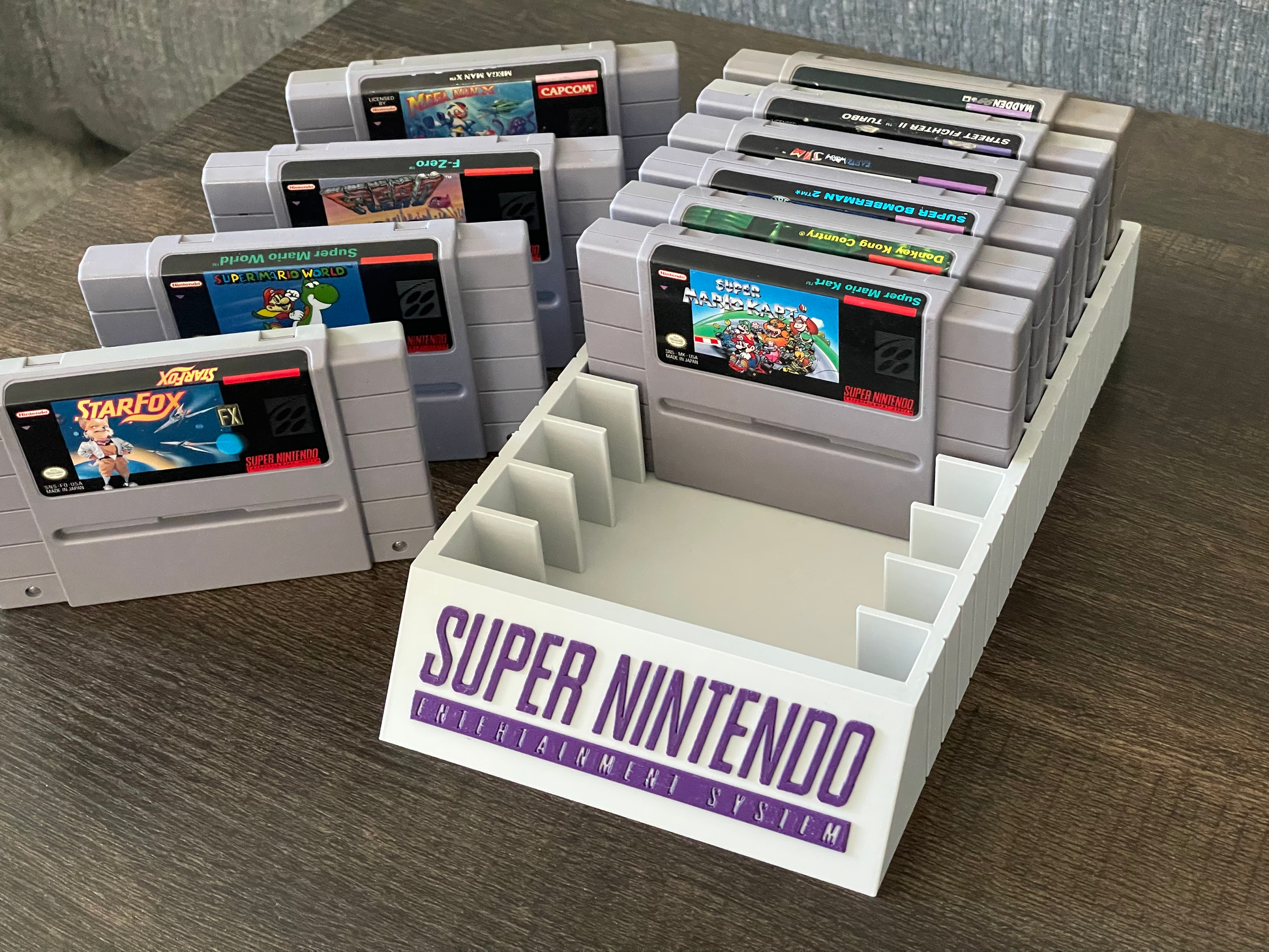 Super Nintendo Entertainment System cartridges on a wooden surface with a branded holder.