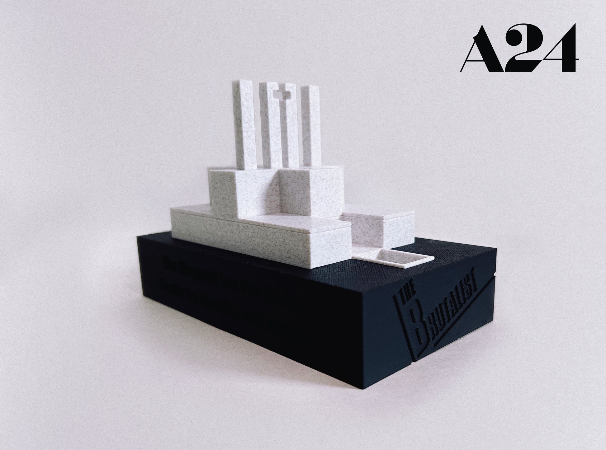 Minimalist sculpture on a black base with 'A24' branding in the corner
