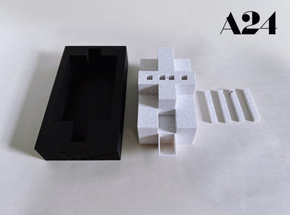 Black rectangular box and white geometric sculpture on a light gray background with 'A24' branding.
