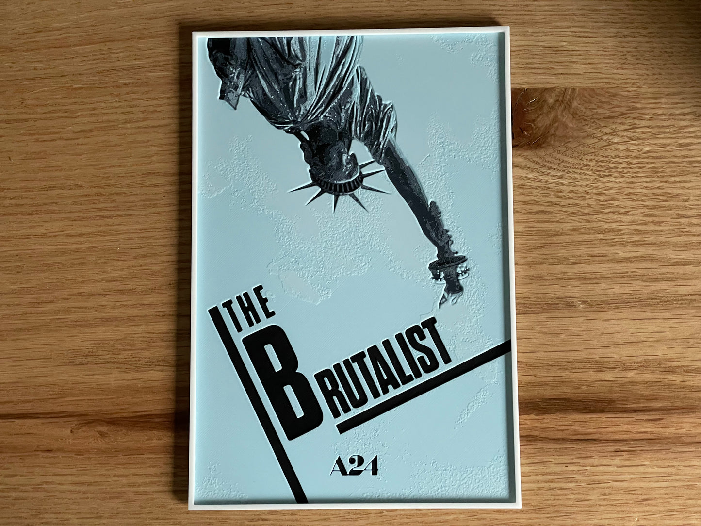 movie poster 'The Brutalist' A24 on a wooden surface
