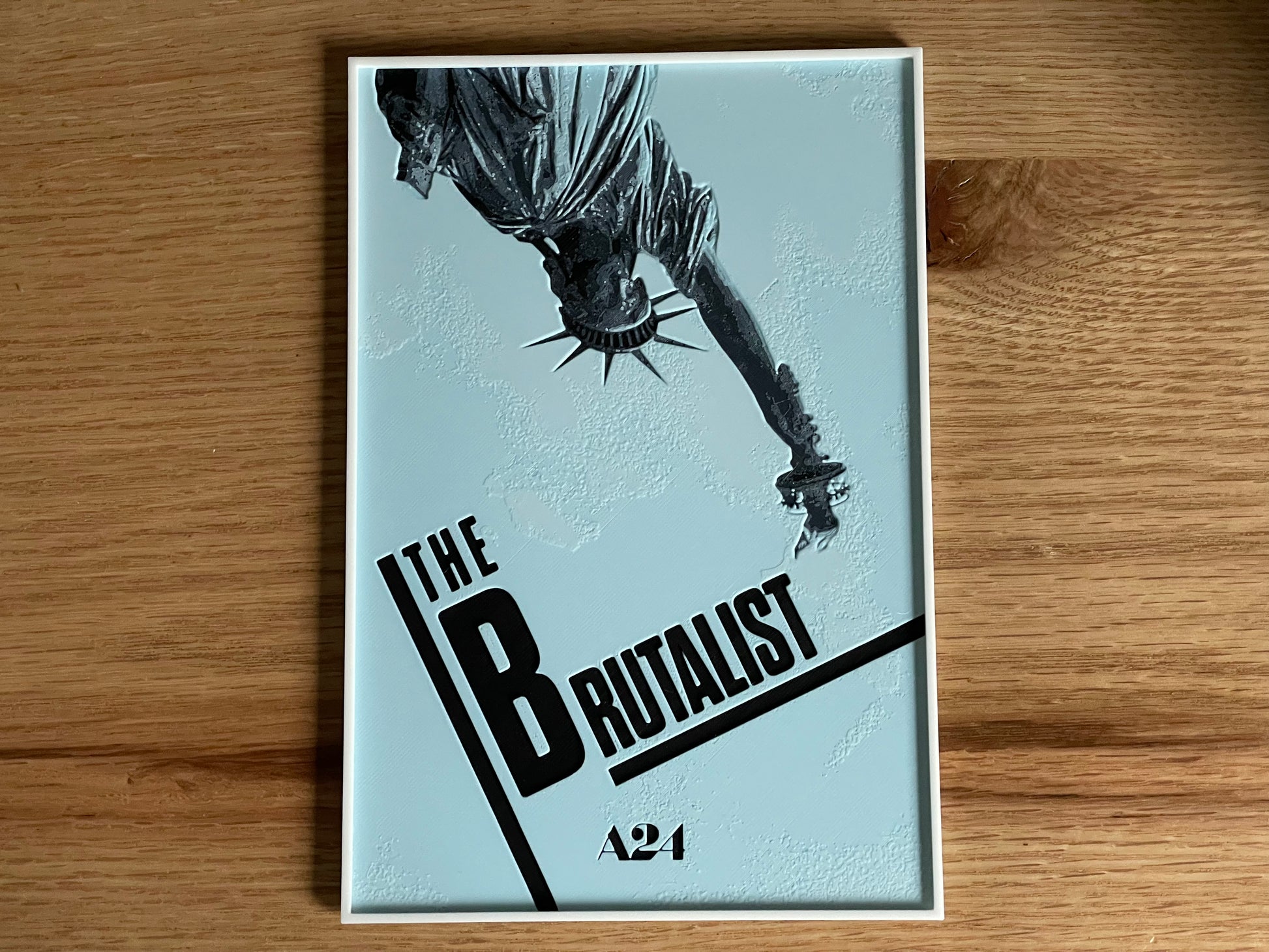 movie poster 'The Brutalist' A24 on a wooden surface