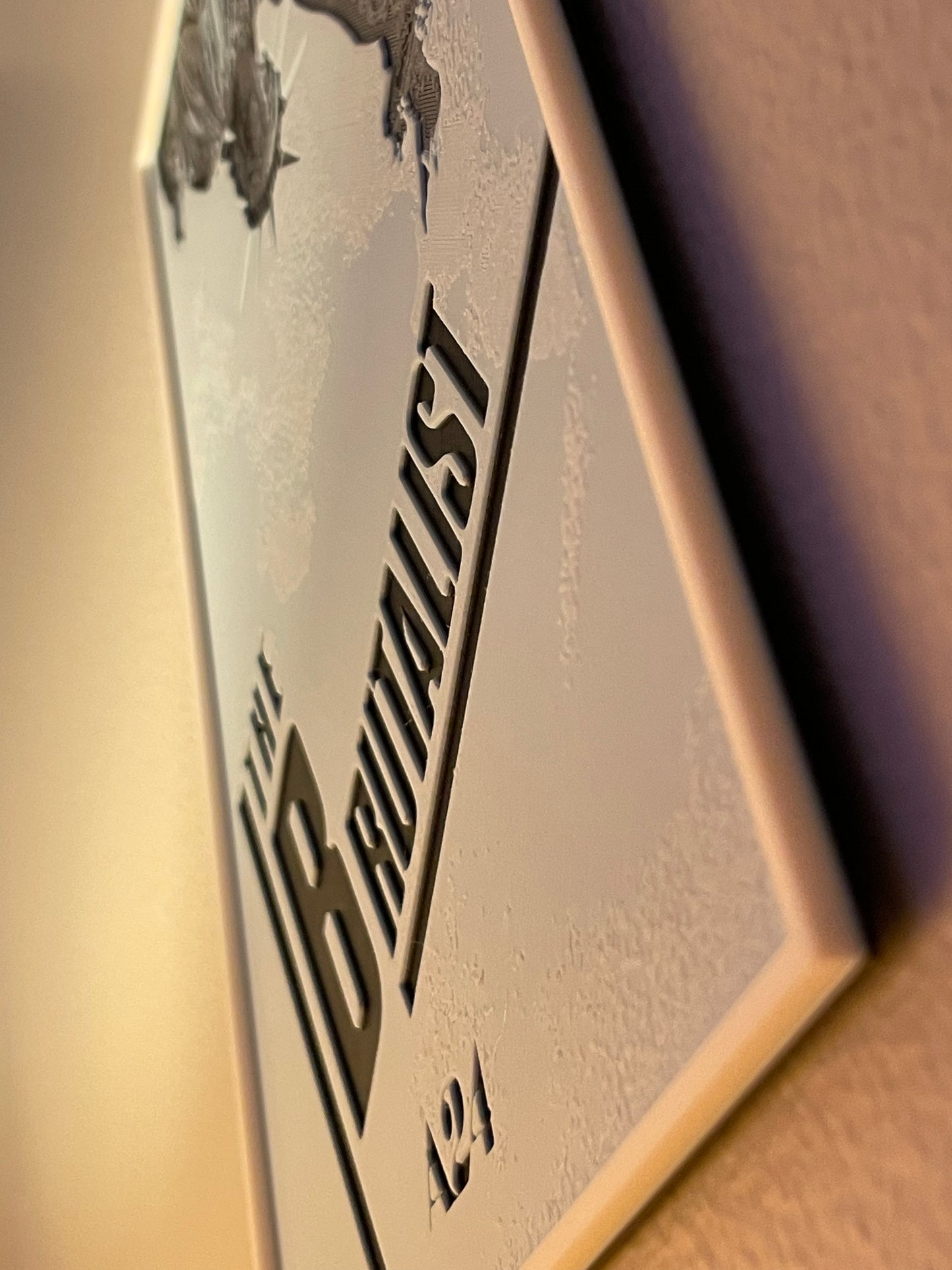 Close-up of a metallic object with 'brutalist' branding on a beige background