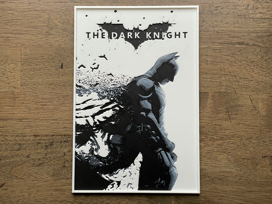 Poster of 'The Dark Knight' with a silhouette of a character on a wooden surface