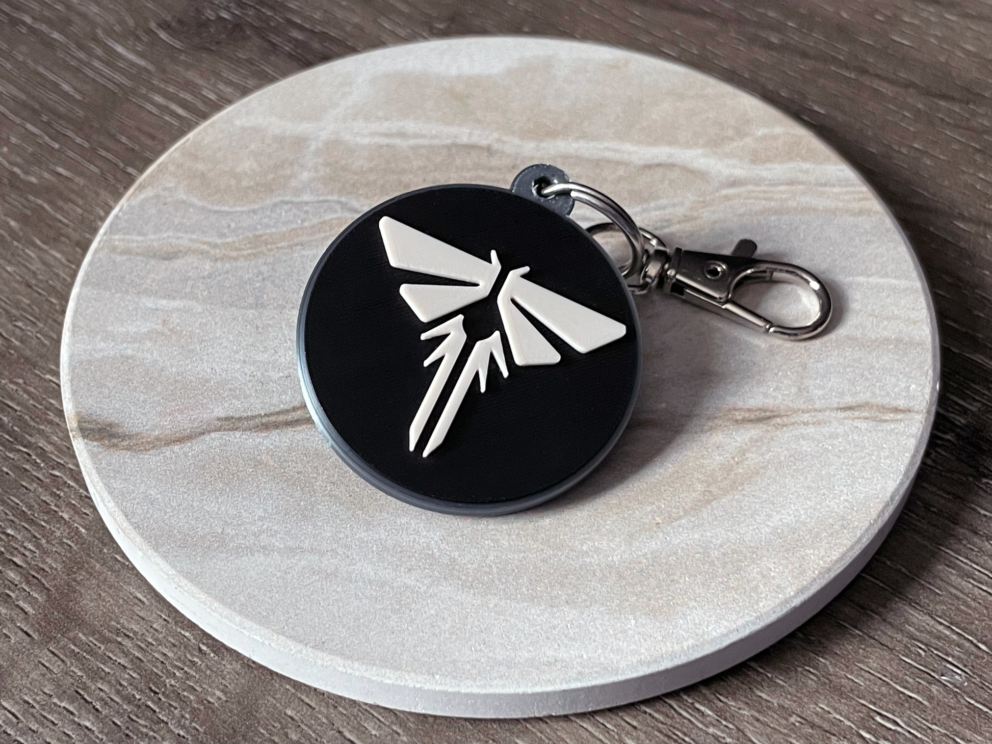 Keychain with a black and white logo on a round stone surface