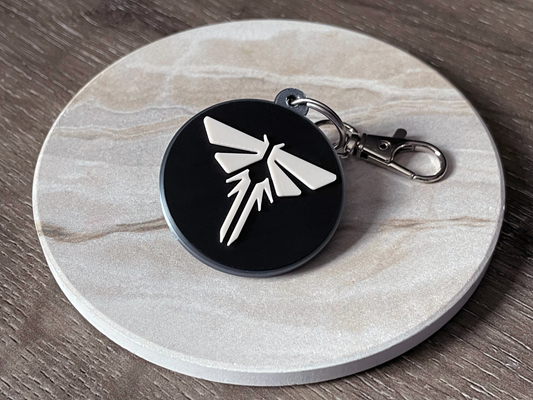 Keychain with a black and white logo on a round stone surface