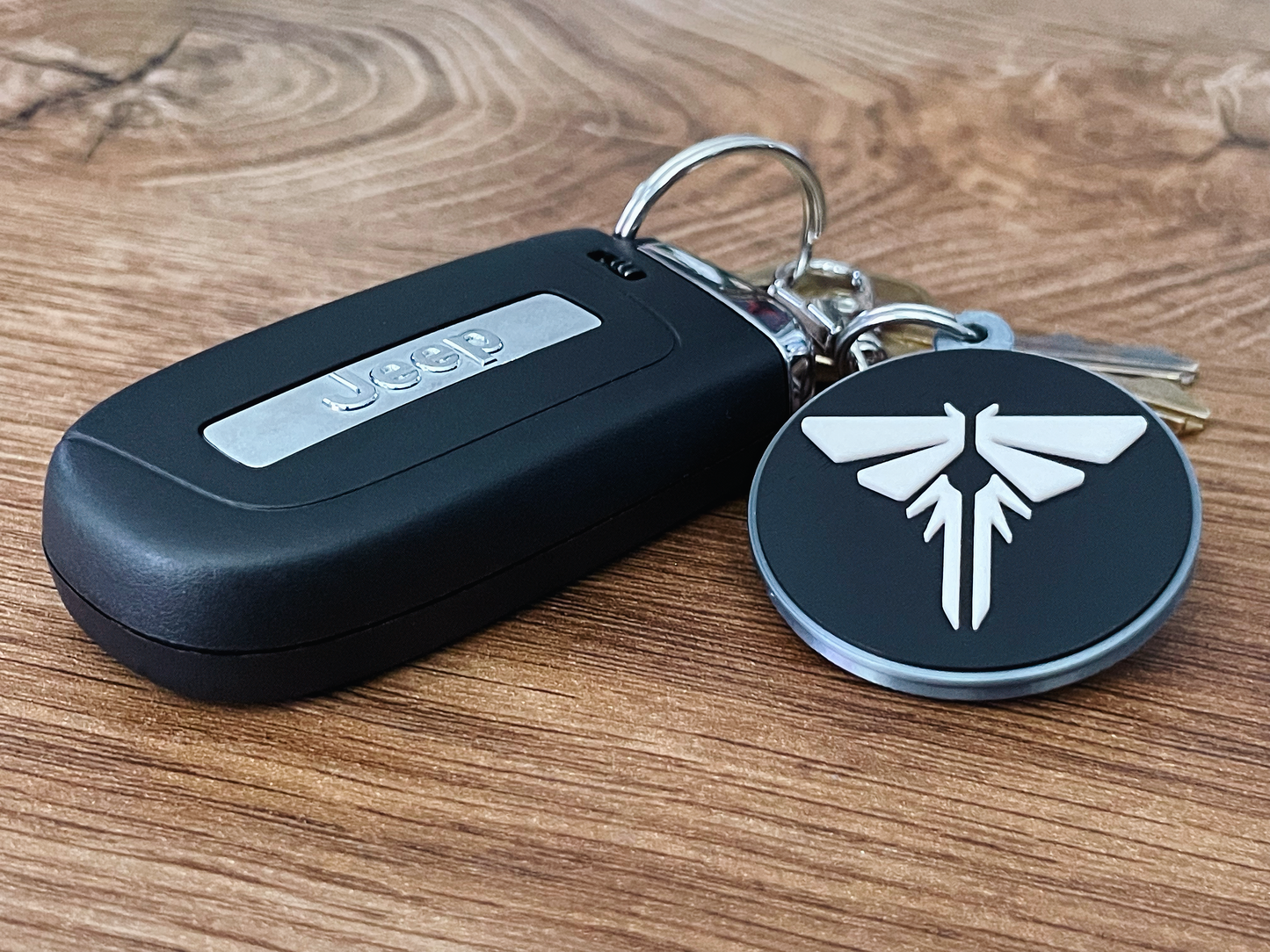 Keychain with a black case and a round tag featuring a white logo on a wooden surface