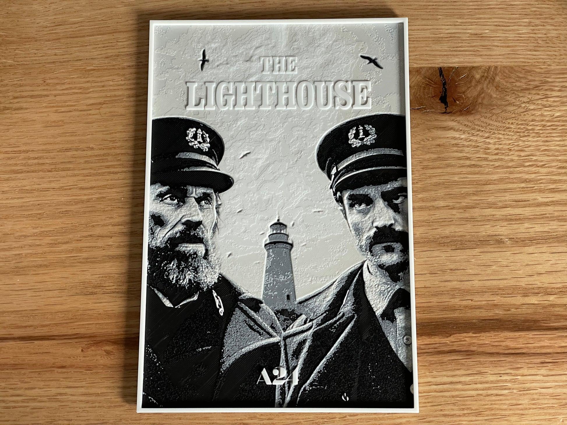 Movie poster for 'The Lighthouse' featuring two men and a lighthouse on a wooden surface.