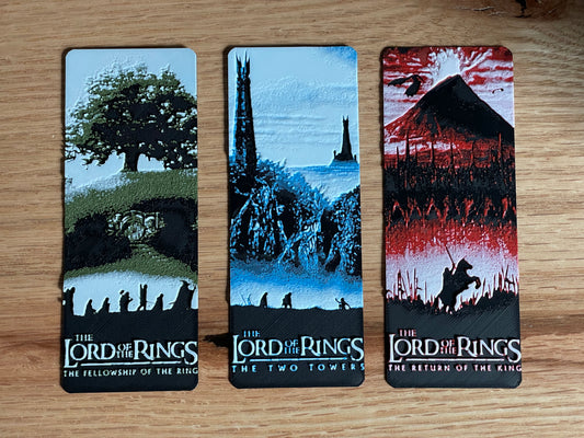 Three 'The Lord of the Rings' bookmarks on a wooden surface