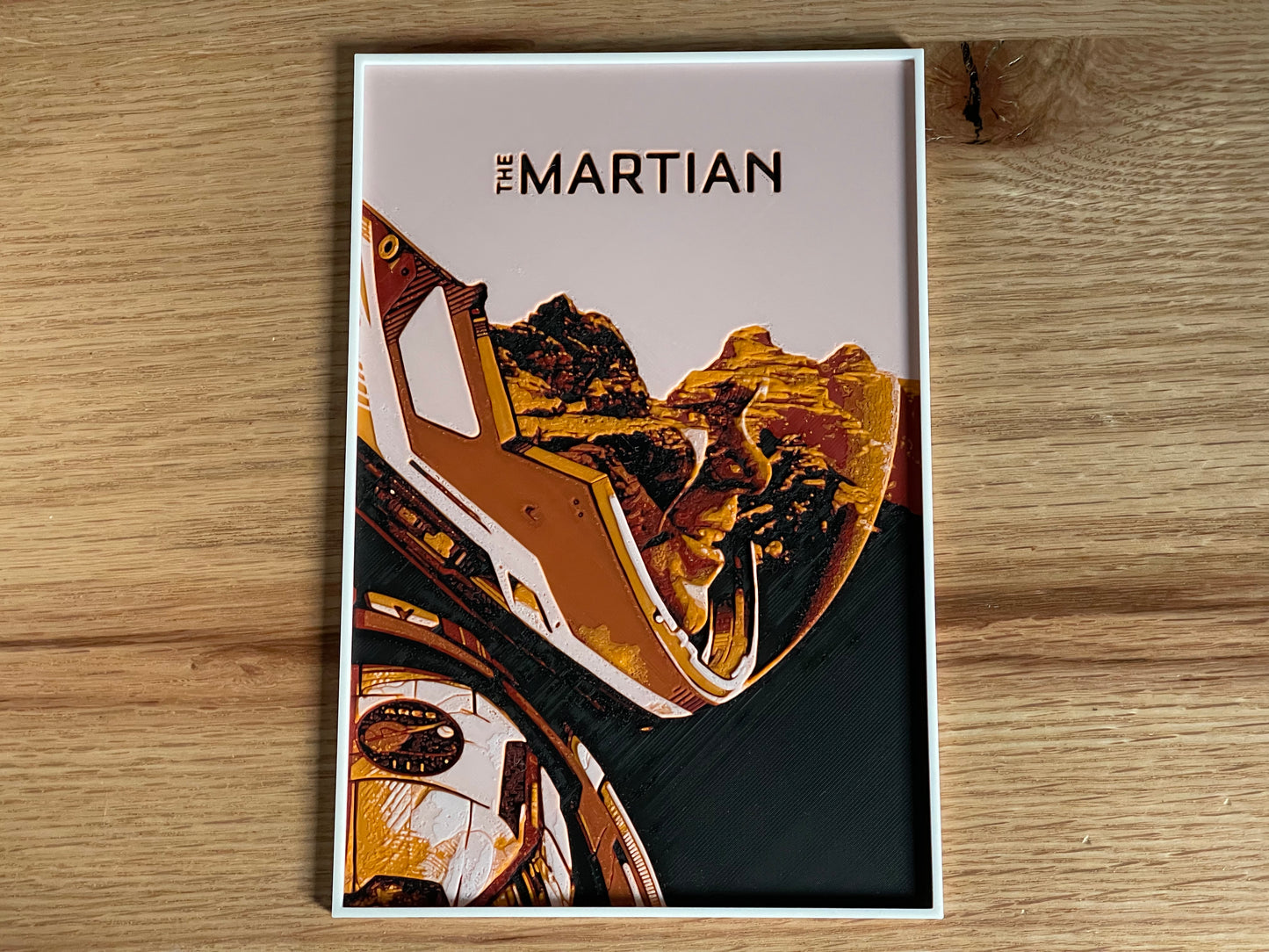 Poster of 'The Martian' with a spacesuit and landscape design on a wooden surface