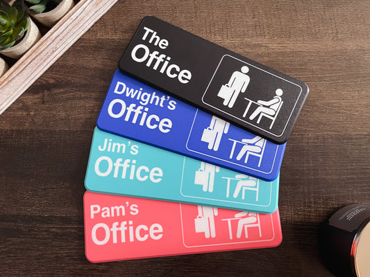 Stack of office-themed nameplates on a wooden surface
