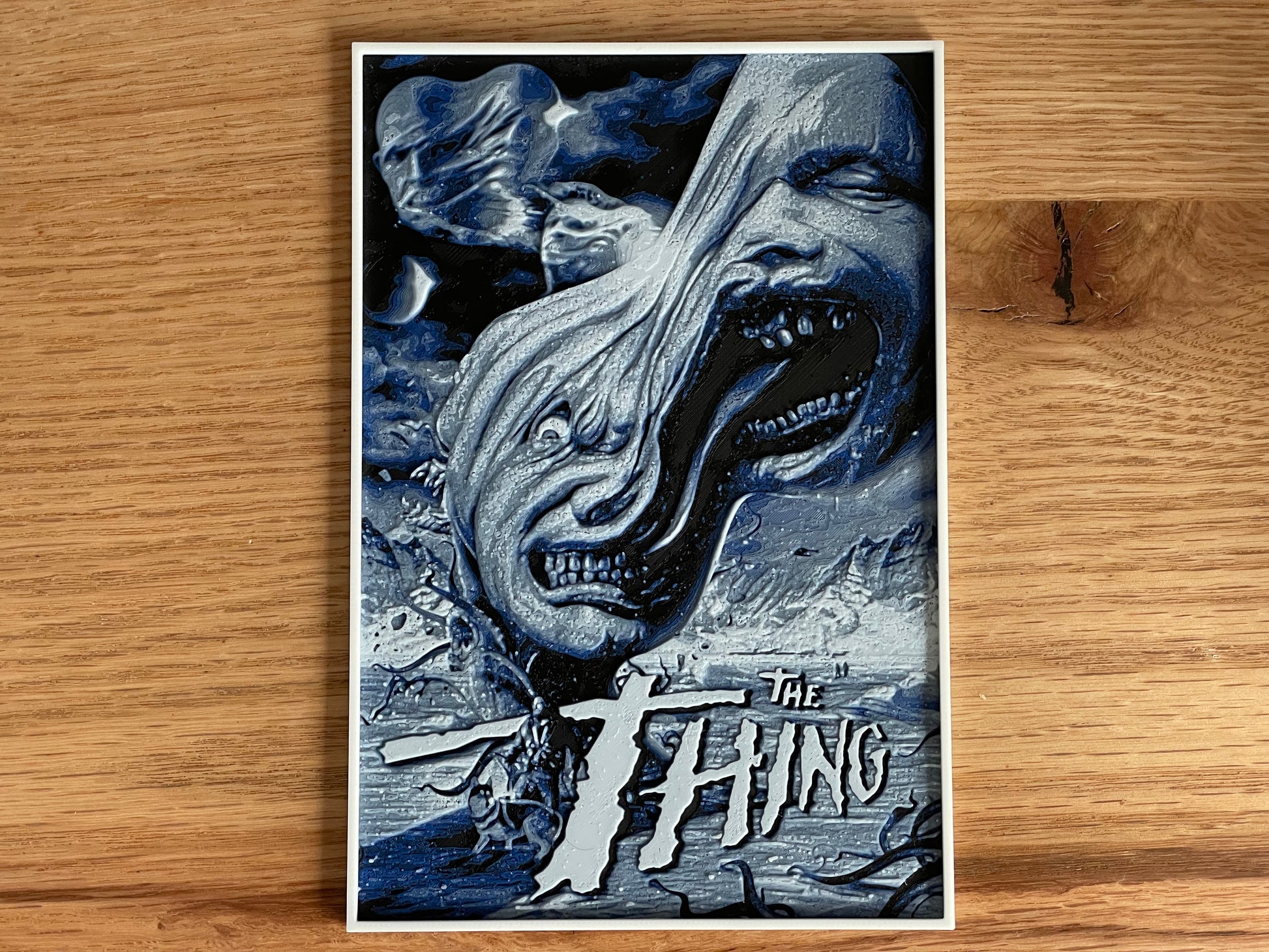Poster of 'The Thing' with a creature's face on a wooden surface