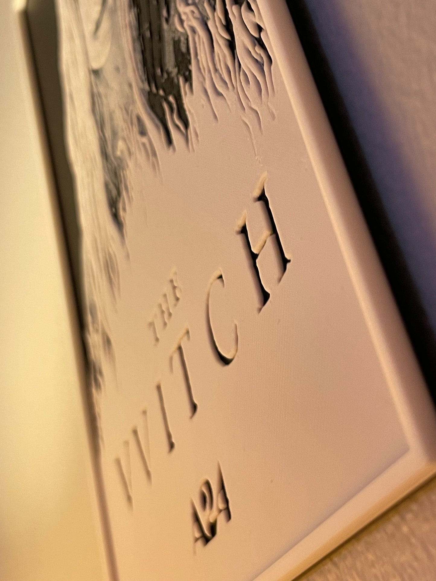 Decorative plaque with 'The Witch' text and number on a plain background