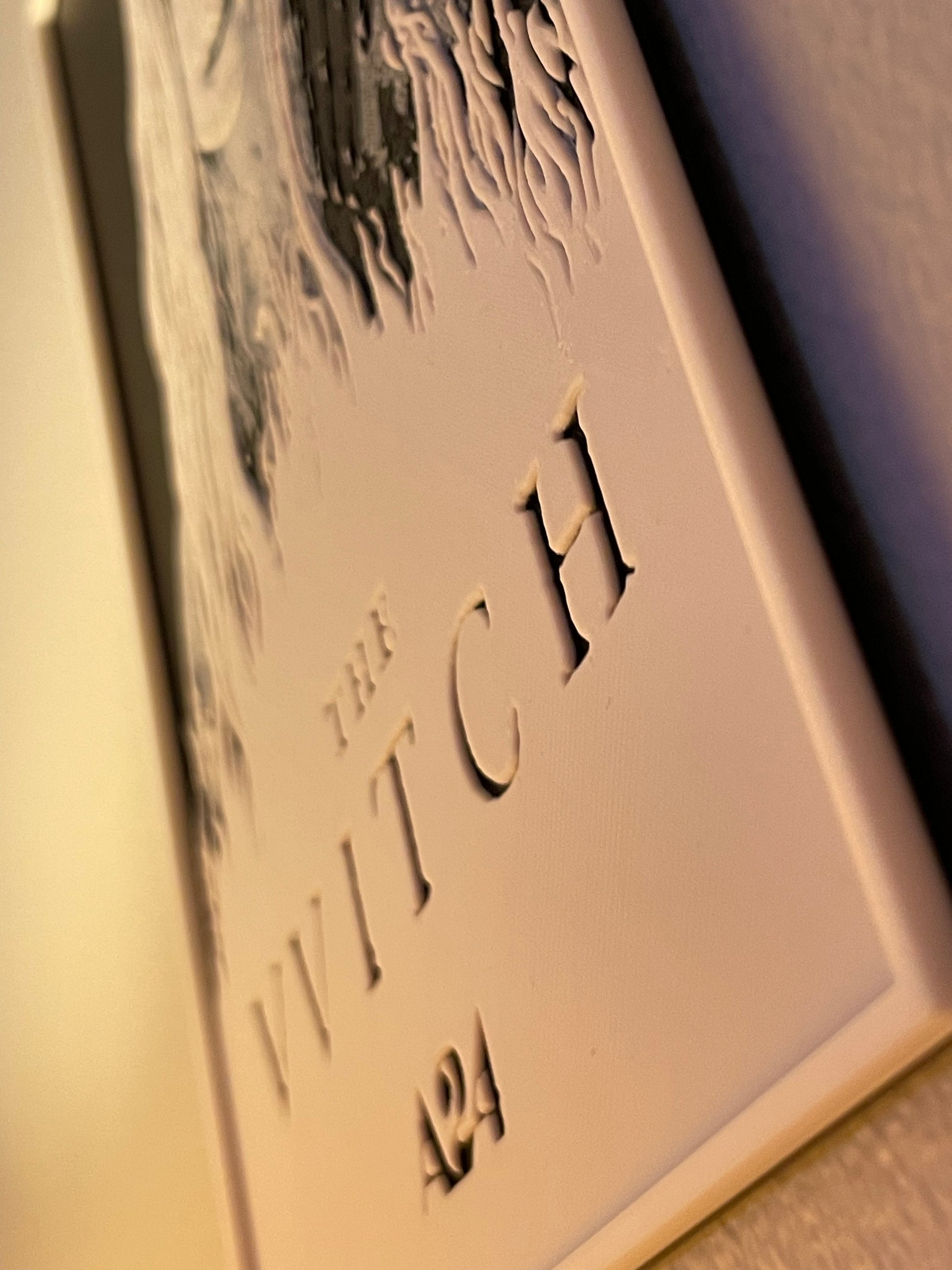 Decorative plaque with 'The Witch' text and number on a plain background